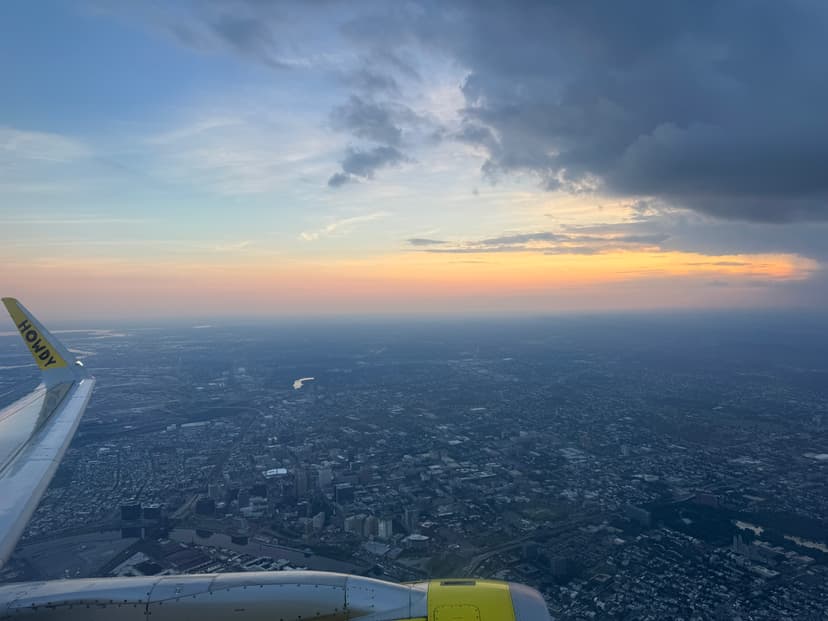 A picture of an airplane wing, over a city, with the word "howdy" on the tail of the wing